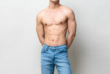 Shirtless muscular male model body on gray isolated background in light studio