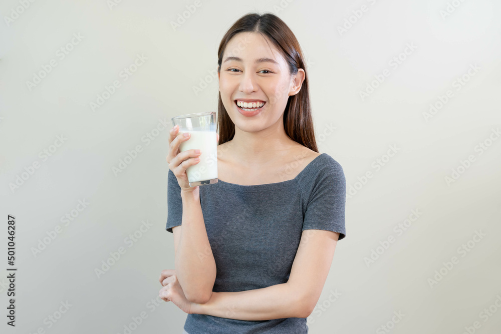 Happy, asian young woman, girl drinking a glass of white fresh, warm or hot dairy milk for calcium, vitamin wholesome good nutrition in morning. lifestyle, product healthy people, Isolated background. Happy, asian young woman, girl drinking a glass of white fresh, warm or hot dairy milk for calcium, vitamin wholesome good nutrition in morning. lifestyle, product healthy people, Isolated background.