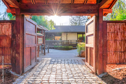 Entrance of Japanese Friendship Garden with stone tiles and double wooden doors in San Jose, CA