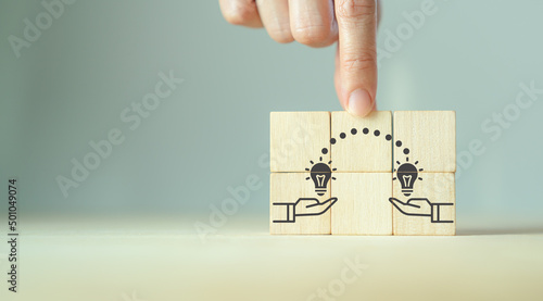 Knowledge and ideas sharing between two people ideas icon on wooden cube. Transferring knowledge, innovation, brainstorming concept. Business strategies to technology evolution reskill and new skill.