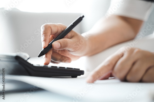 Woman is calculating annual tax with calculator and filling form of Individual Income Tax Return. Season to pay Tax and Budget planning concept. photo