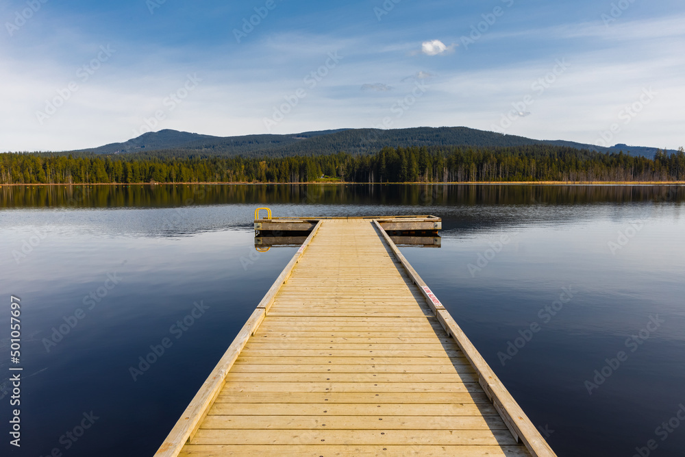 Idyllic view of the wooden pier in the lake with mountain scenery background in the early morning.
