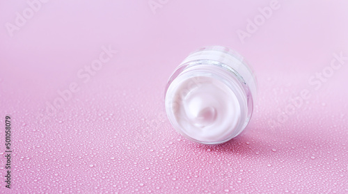 cream jar on pink background with water drops