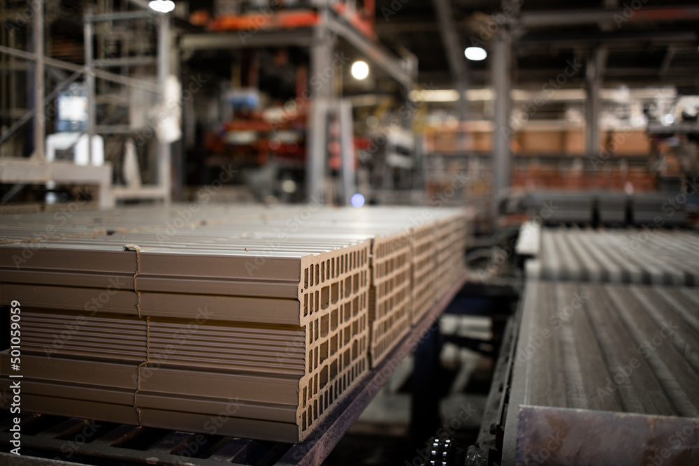Factory interior and industrial production of clay bricks for building industry. Conveyer belt machine moving bricks into heat oven for baking process. Factory interior and industrial production of clay bricks for building industry. Conveyer belt machine moving bricks into heat oven for baking process.
