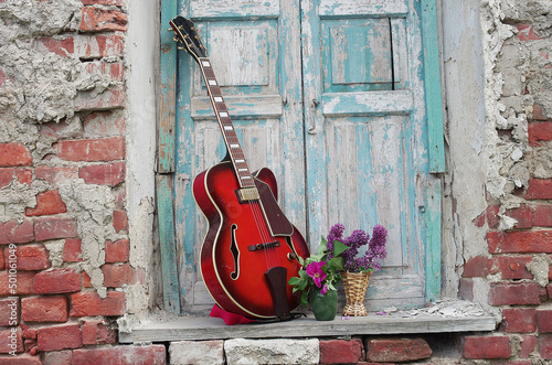 Jazz electric guitar and bouquets of flowers in the window opening. © yrafoto