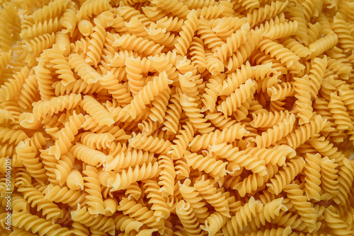 Raw uncooked fusilli pasta, close up background, texture