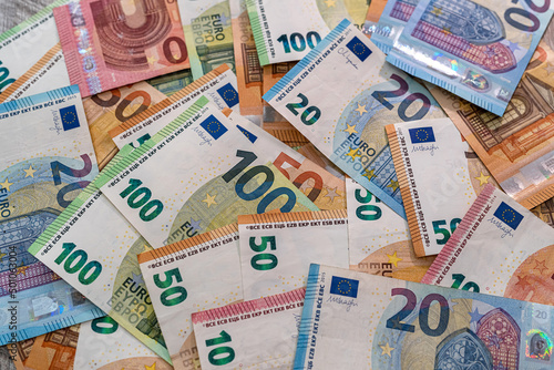 Beautiful multicolored new euro banknotes scattered in a pile on a spacious table.