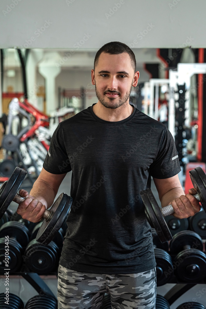 Handsome young man with a beautiful figure works as a fitness trainer in a prestigious gym. Handsome young man with a beautiful figure works as a fitness trainer in a prestigious gym.