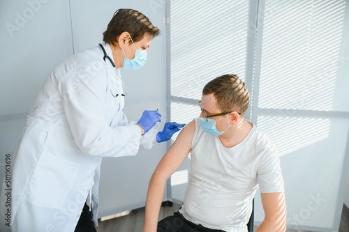 Close up of a Doctor making a vaccination in the shoulder of patient, Flu Vaccination Injection on Arm, coronavirus, covid-19 vaccine disease preparing for human clinical trials vaccination shot. © Serhii