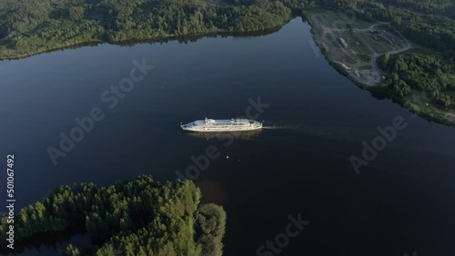 Cruise ship sails on water surrounded by forest