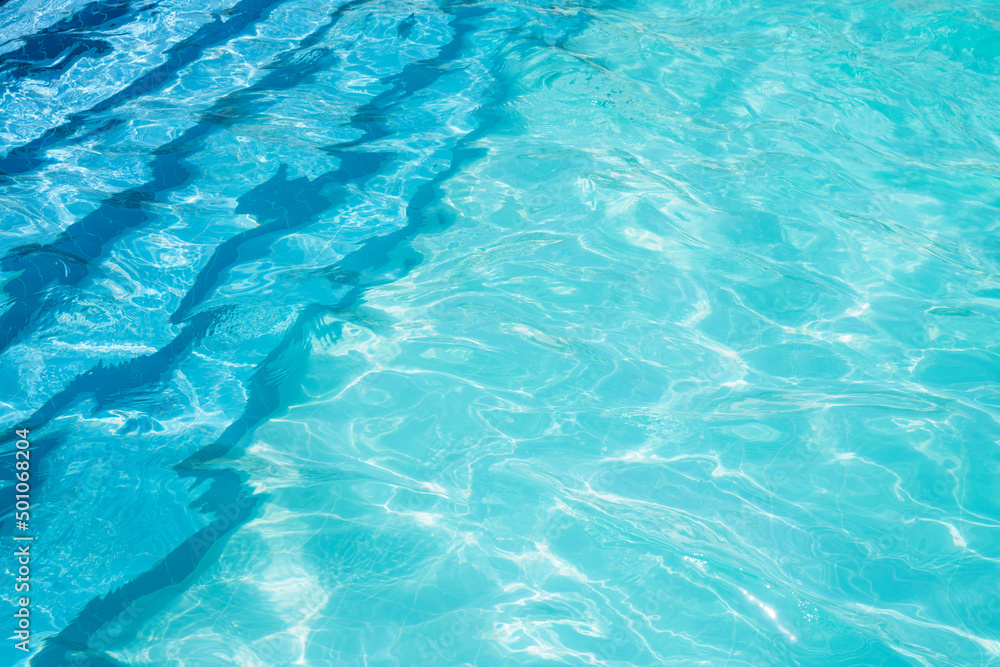 Ladder in the pool and turquoise textured water background. Reflection of the sun in the pool. Ladder in the pool and turquoise textured water background. Reflection of the sun in the pool.