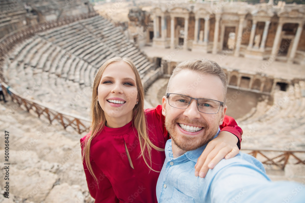 Happy lover Couple Tourist taking selfie photo background Amphitheater in Hierapolis ancient city Pamukkale Turkey sunlight