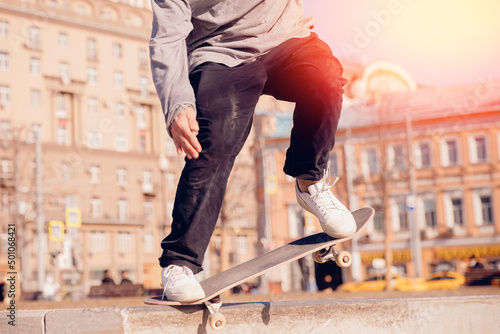 Man young skateboarder legs skateboarding skatepark on sunset. Concept tricks and jumping on skateboard