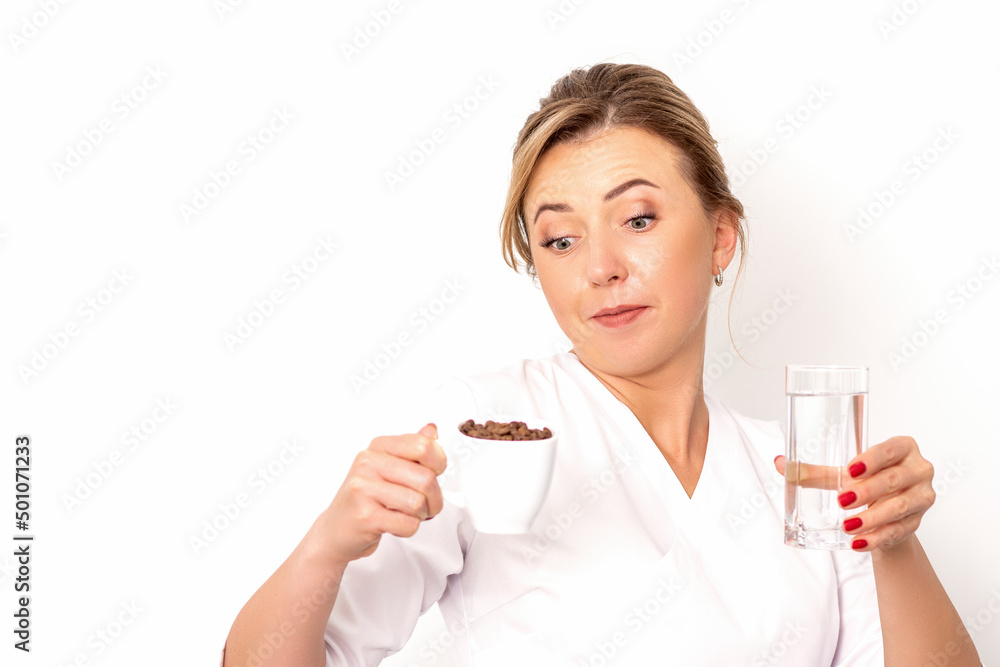 Coffee with water. The female nutritionist holds a cup of coffee beans and a glass of water in her hands on white background Coffee with water. The female nutritionist holds a cup of coffee beans and a glass of water in her hands on white background