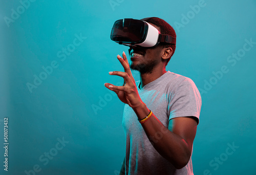 Canvas Young man having fun with interactive virtual reality headset, using modern technology with futuristic 3d vision