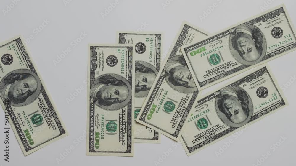 A human casually throws bucks on the table in a chaotic manner. On a flat surface is a lot of hundred dollar bills. Benjamin Franklin is depicted on the money A human casually throws bucks on the table in a chaotic manner. On a flat surface is a lot of hundred dollar bills. Benjamin Franklin is depicted on the money