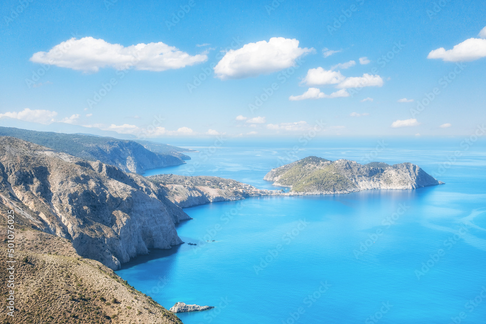 Scenic cliffs near sunny sea shore on a bright clear blue day in Greece. Gialos pebble beach with turquoise water and clear blue sky, Lefkada island, Ionian sea coast