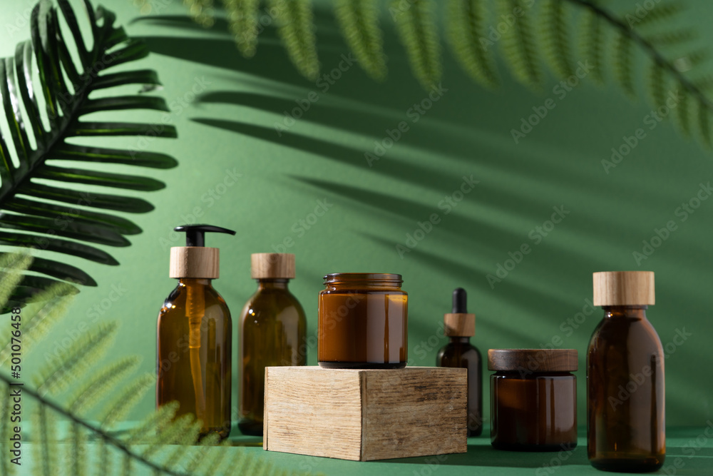 Bottles for cosmetics and cream on a pedestal, green background with ...