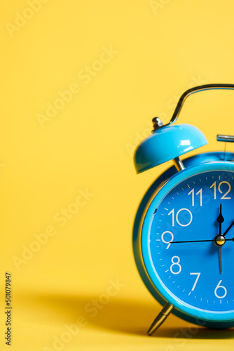 detail of retro blue alarm clock on yellow background