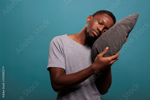 Photography Tired man using comfortable pillow to get sleepy and take nap over blue background