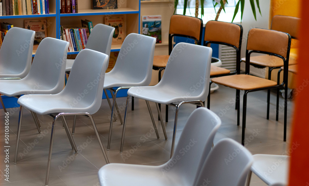 empty rows of white and brown office chairs in the library conference room against the background of bookshelves