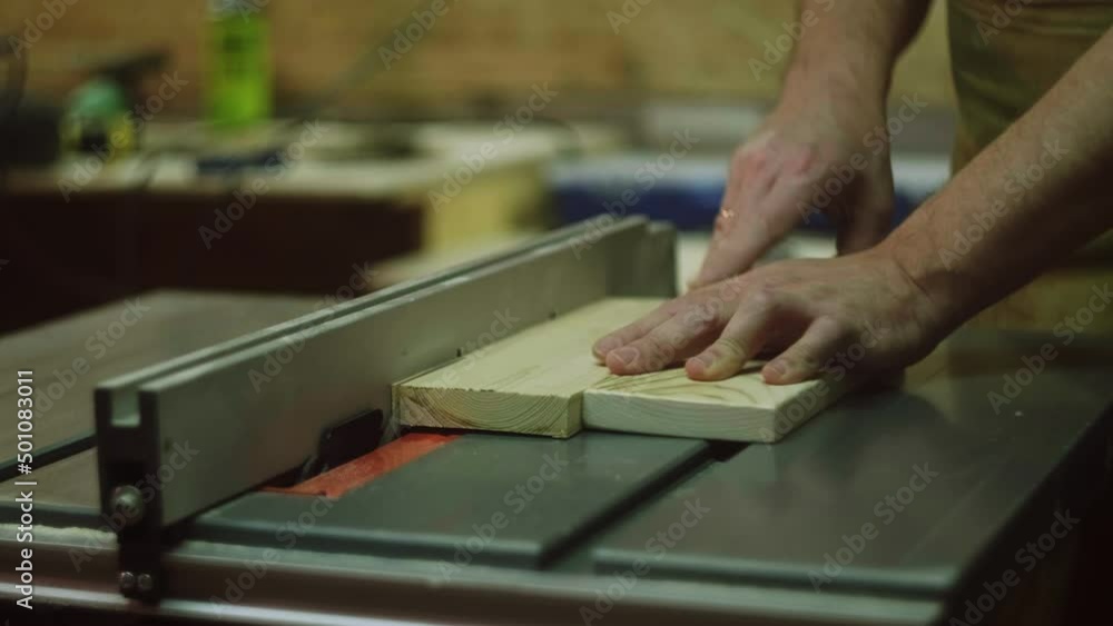 A mature man makes a right angle with a square and saws boards on a circular saw A mature man makes a right angle with a square and saws boards on a circular saw