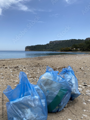 Two plastic bags with garbage are lying on the beach. In the background the sky. Low angle view. The concept of environmental pollution and Earth Day.