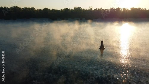 drone flies around a buoy on the river, morning mist over the water, fog