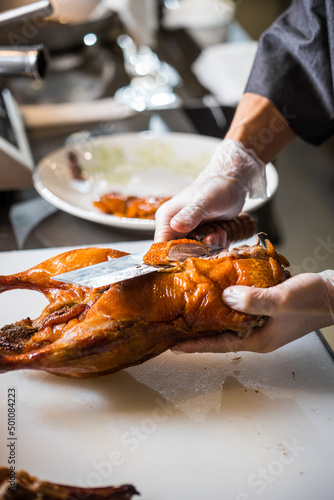 chinese chef cooking peking roasted duck at the kitchen of restaurant