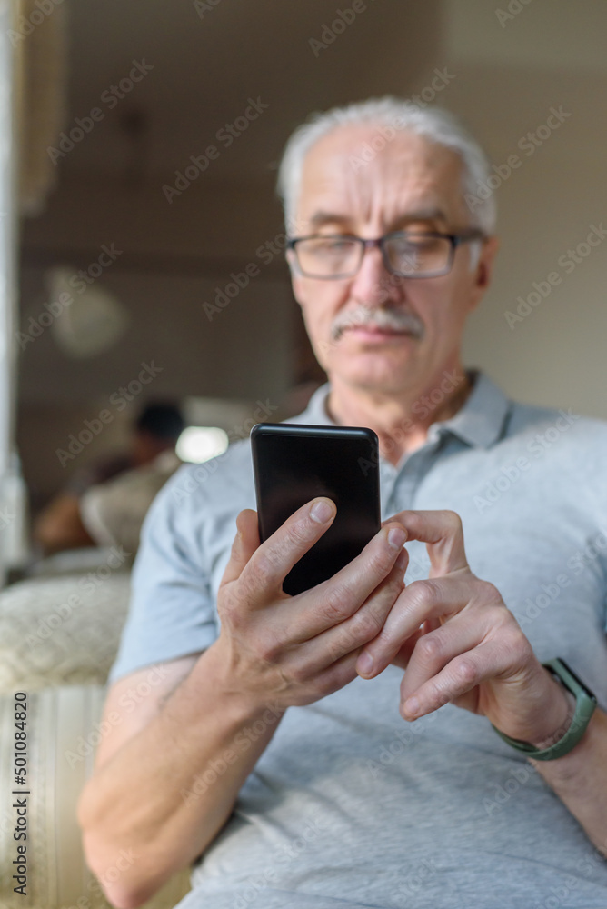 Senior man in eyeglasses using mobile phone at home Senior man in eyeglasses using mobile phone at home