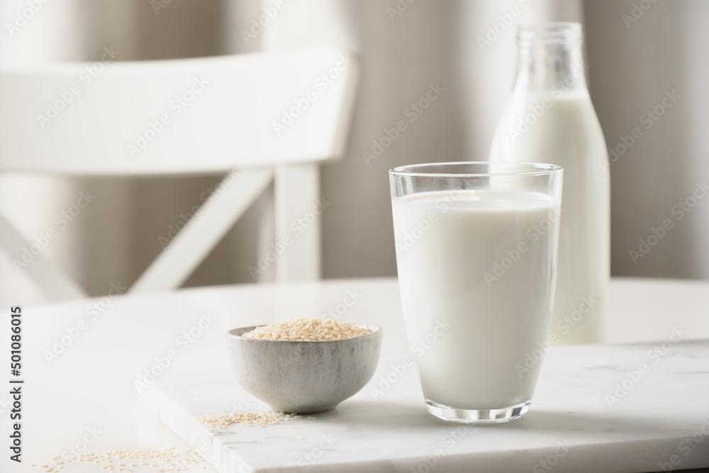 Sesame milk and sesame seeds in bowl on white kitchen background. Lactose free. Close up. Lack of cholesterol. vitamins, amino acids, fiber, minerals