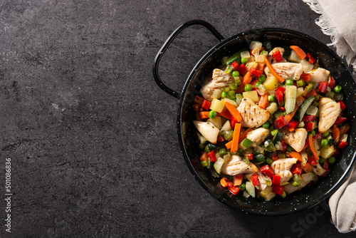 Chicken stir fry and vegetables on black stone. Top view