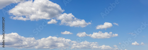 Panoramic view of white cumulus clouds on midday blue bottomless sky background high contrast