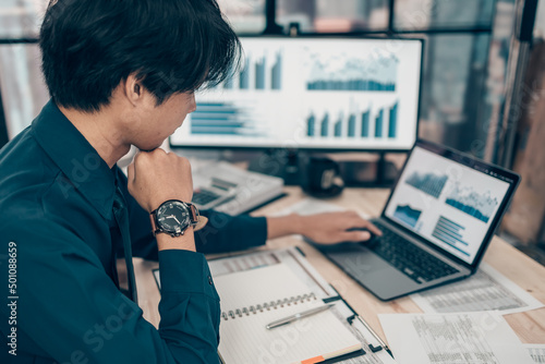 Investors wearing watch and working on desk office and using laptop  to check graph, chart, tracking cost, balance, projit and  currency. Accounting and  Financial concept. photo