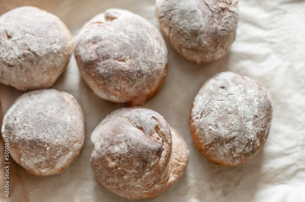 Fresh baked wheat-rye buns on baking paper, top view. Fresh baked wheat-rye buns on baking paper, top view.