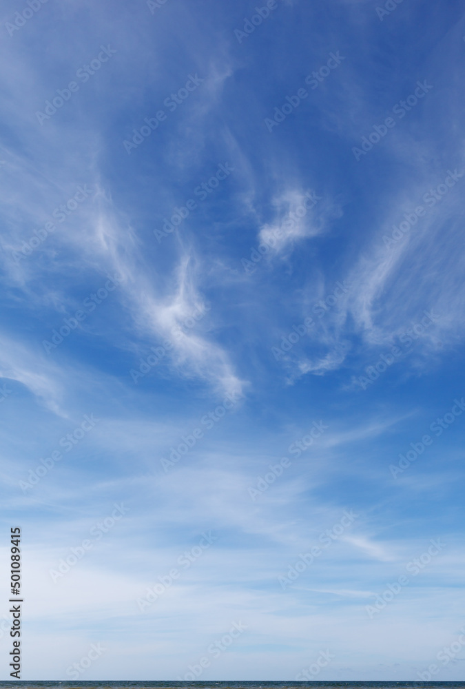 Beautiful blue sky over the sea with cirrus clouds. Horizon line