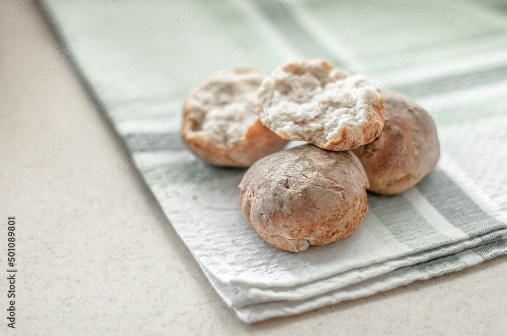 Fresh baked wheat-rye rolls on a cotton napkin on a table. Fresh baked wheat-rye rolls on a cotton napkin on a table.