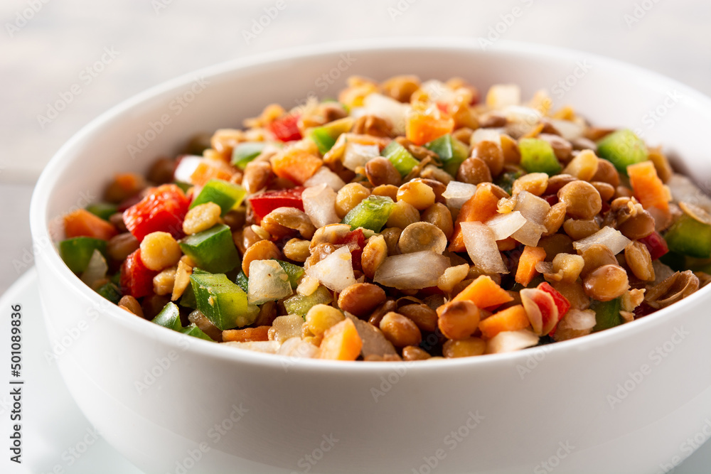 Lentil salad with peppers,onion and carrot in bowl on wooden table. Close up Lentil salad with peppers,onion and carrot in bowl on wooden table. Close up