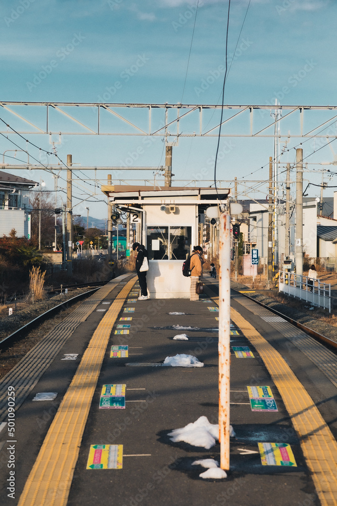 田舎の駅で電車を待つ人