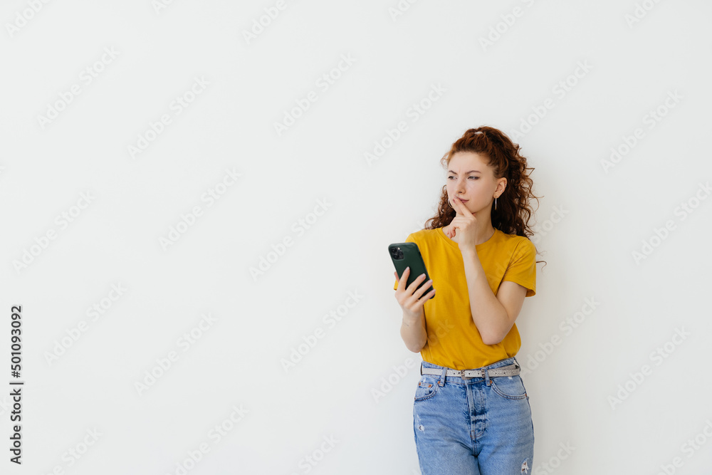 Young woman reading message on smartphone and smiling, social networking while standing over white background Young woman reading message on smartphone and smiling, social networking while standing over white background