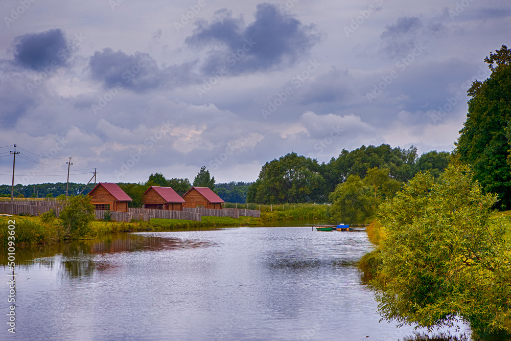Belarus Travel Places. Tiny Pier and Line of Wooden Houses Places Together in Dukora Estate in Belarus. Belarus Travel Places. Tiny Pier and Line of Wooden Houses Places Together in Dukora Estate in Belarus.