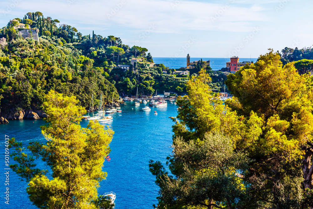 Fishing boats moored on water in harbor of Ligurian and Mediterranean Sea near coastline of Riviera di Levante of National park Cinque Terre Coast with blue sky, Riomaggiore village, Liguria, Italy.