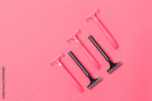 Skin Care Ideas. Flatlay Upper View Image of Five Colorful Pink and Black Disposable Razors Shavers Placed Reversed Over Trendy Pink Coral Background.