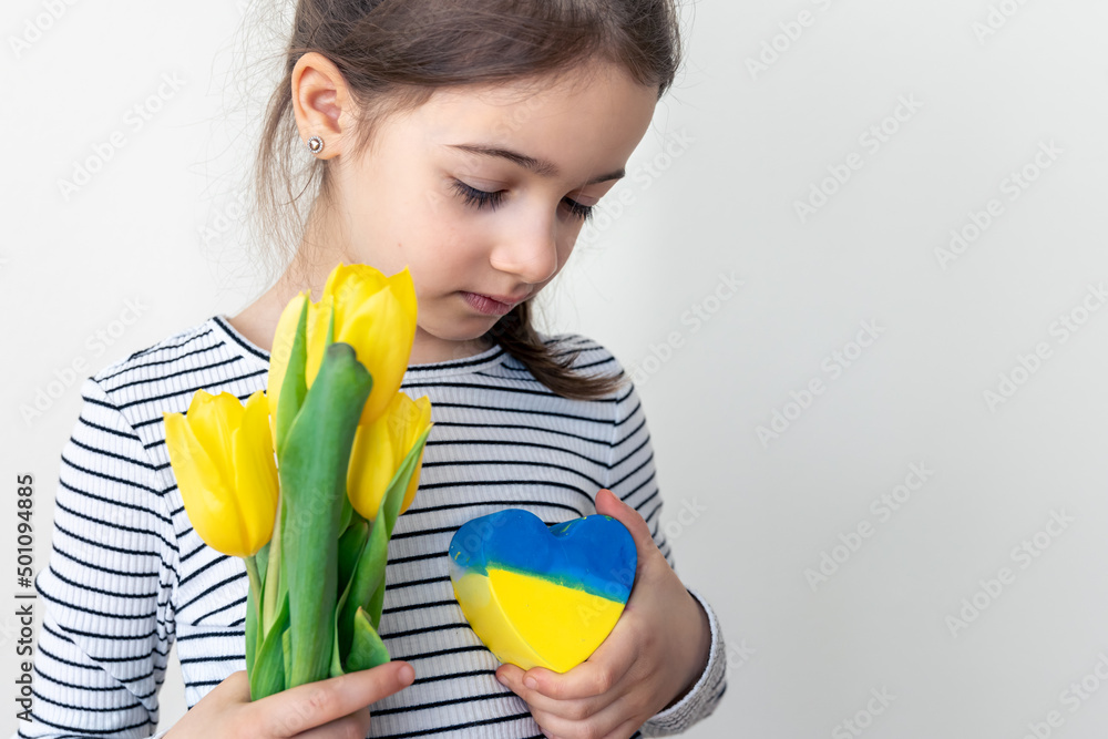 Little girl with a bouquet of tulips and a heart with the flag of Ukraine. Little girl with a bouquet of tulips and a heart with the flag of Ukraine.
