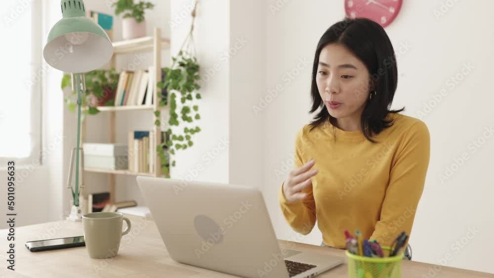 Happy young asian woman working from home having a video call on laptop computer - Entrepreneur and freelancer people concept with chinese female talking on meeting online from home office Happy young asian woman working from home having a video call on laptop computer - Entrepreneur and freelancer people concept with chinese female talking on meeting online from home office