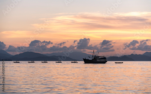 old fishing ship on the sea with Colorful ocean beach sunset. © xiaoliangge