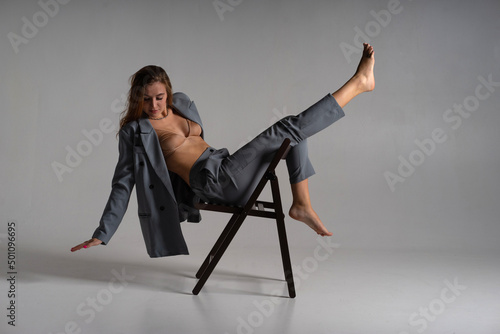 Fotografie A model girl poses professionally for a photographer on a chair in complex acrobatic recumbent poses