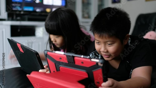 two children addicted tablet, asian kid watching cartoon
