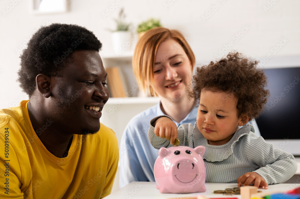 Child is Putting a Coin into a Piggy- bank. Savings Bank Accounts for Kids Concept. Child is Putting a Coin into a Piggy- bank. Savings Bank Accounts for Kids Concept.