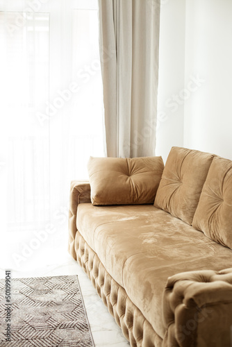 Modern comfortable beige sofa by the window in a stylish living room. Interior design concept.